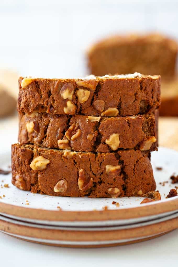 three stacked slices of oat flour banana bread with walnuts on two white plates